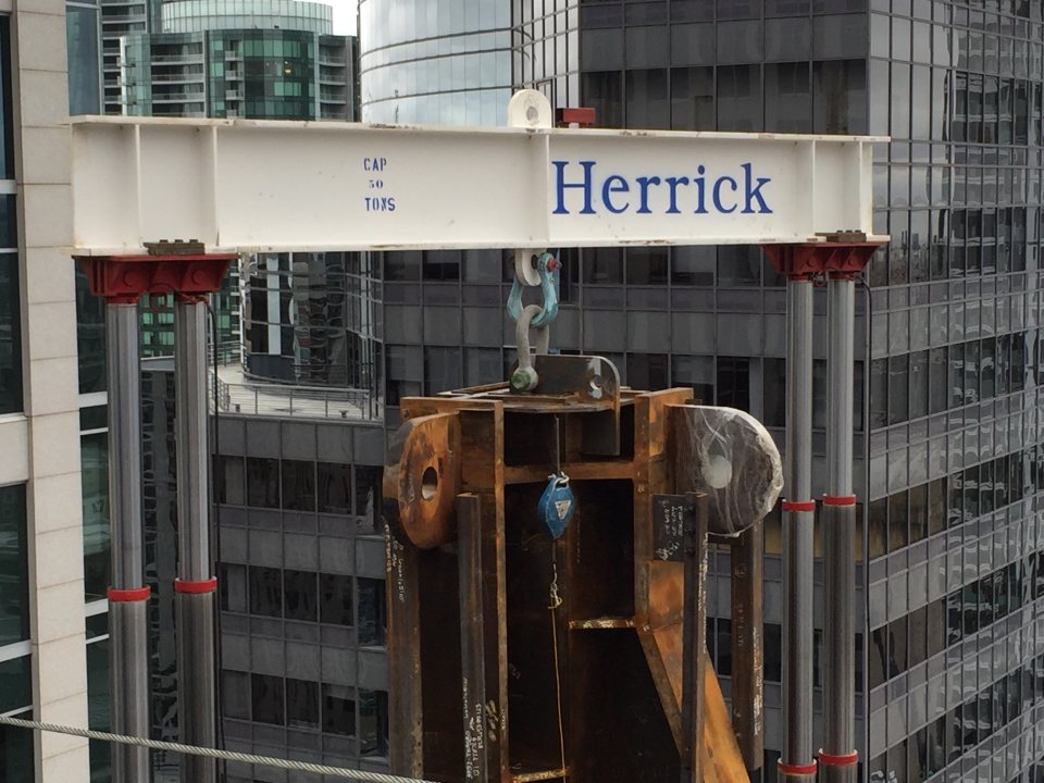 Ironworker beside a steel beam bearing the Herrick name